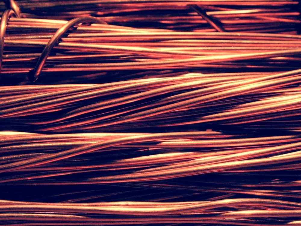 Bundled strands of bright copper wire, lit so the metal glows.