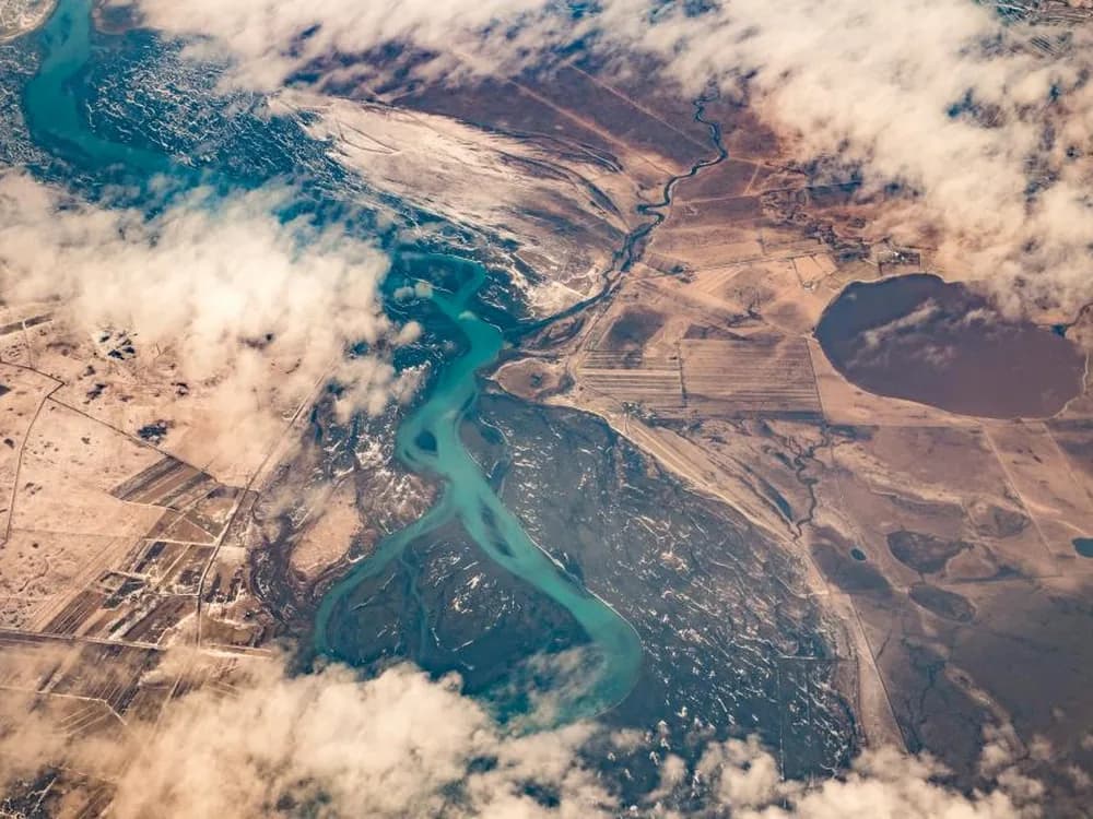 Aerial view of open land traced by a winding river.
